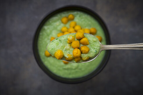 Schale mit grünem Gazpacho mit Avocado und gerösteten Kichererbsen mit Kurkuma, auf Löffel, Nahaufnahme - LVF07433