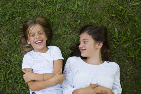 Two sisters lying together on a meadow having fun - LVF07441