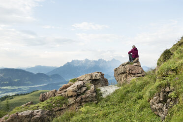 Österreich, Tirol, Fieberbrunn, Wildseeloder, Frau sitzt auf Stein mit Blick auf Berglandschaft - PSIF00065