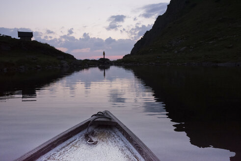 Österreich, Tirol, Fieberbrunn, Wildseeloder, Bug eines Bootes auf dem Wildsee mit Person am Seeufer in der Abenddämmerung - PSIF00071