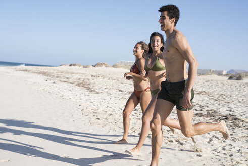 Glückliche, sorglose Freunde, die am Strand zum Meer laufen - PACF00080