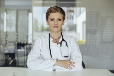 Porträt einer selbstbewussten Ärztin, mit verschränkten Armen, lizenzfreies Stockfoto