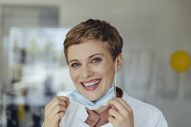 Portrait of a confident female doctor, removing surgical mask - MFF04514