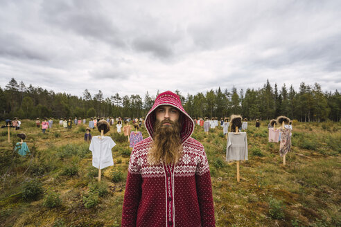 Finland, Suomussalmi, Man standing in front of The Silent People, art project with crowd of scare crows - KKAF01704