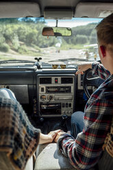 Romantisches Paar auf einer Autoreise, das sich im Auto an den Händen hält - VPIF00600