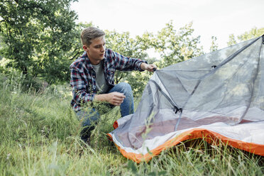 Junger Mann beim Zelten in der Natur, Zelt aufstellen - VPIF00612