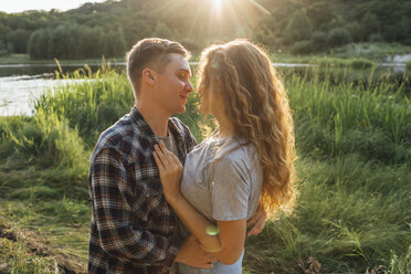 Romantisches Paar, das Zeit in der Natur verbringt und sich bei Sonnenuntergang küsst - VPIF00626