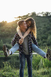 Romantic couple spending time in nature, embracing at sunset - VPIF00633