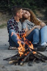 Romantisches Paar sitzt am Lagerfeuer am Flussufer - VPIF00636