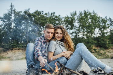 Romantisches Paar sitzt am Lagerfeuer am Flussufer - VPIF00639