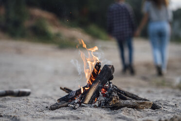 Burning campfire at the riverside, couple in background - VPIF00645