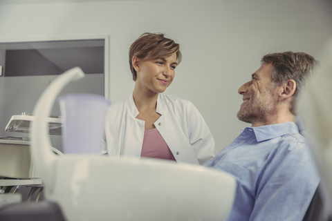 Zahnärztin im Gespräch mit ihrem Patienten vor der Behandlung, lizenzfreies Stockfoto