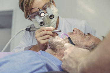 Patient getting dental treatment, dentist using dental drill and head magnifiers and light - MFF04547