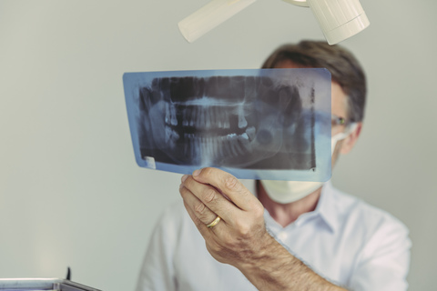 Zahnarzt betrachtet Röntgenbild vor der Behandlung, lizenzfreies Stockfoto