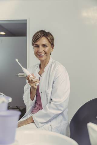 Zahnärztin mit elektrischer Zahnbürste, lizenzfreies Stockfoto