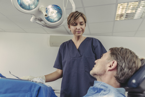 Zahnchirurg im Gespräch mit dem Patienten vor der Behandlung, lizenzfreies Stockfoto