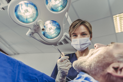 Zahnchirurg bei einem chirurgischen Eingriff an einem Patienten, lizenzfreies Stockfoto