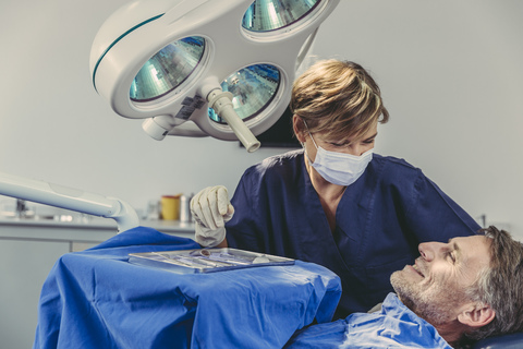 Patientin lächelt den Zahnarzt nach erfolgreicher Behandlung an, lizenzfreies Stockfoto