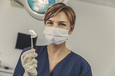 Dental surgeon wearing surgical mask, holding swab - MFF04581