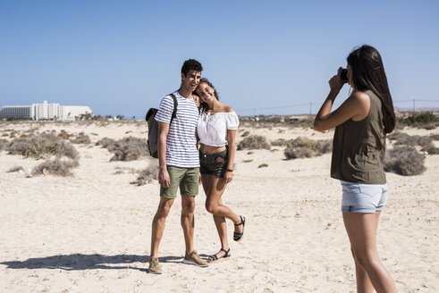 Junge Frau fotografiert ein junges Paar am Strand - PACF00104