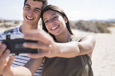 Junges Paar, das sich am Strand amüsiert und mit dem Smartphone Selfies macht - PACF00109