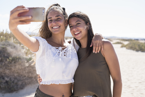 Freundinnen haben Spaß am Strand und machen Smartphone-Selfies, lizenzfreies Stockfoto