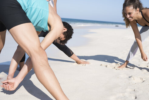 Spanien, Kanarische Inseln, Fuerteventura, zwei junge Frauen und ein junger Mann beim Sport am Strand - PACF00123