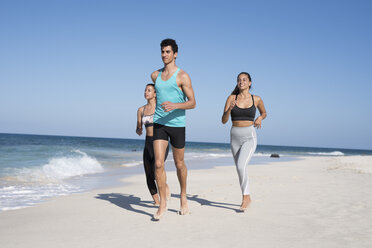 Spanien, Kanarische Inseln, Fuerteventura, zwei junge Frauen und ein junger Mann laufen am Strand - PACF00130