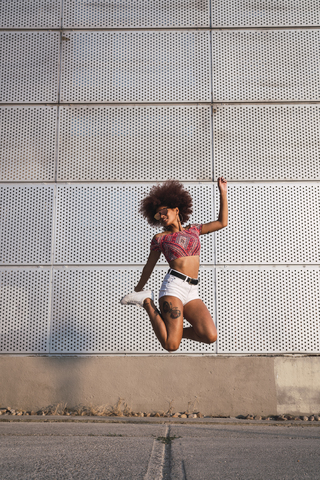 Modische junge Frau springt in die Luft, lizenzfreies Stockfoto