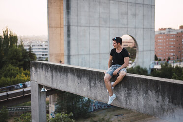 Mann sitzt auf einer Mauer und genießt die Aussicht im Abendlicht - KKAF01757