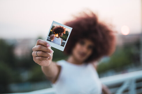 Junge Frau, die ein Sofortfoto von sich zeigt, Nahaufnahme - KKAF01767