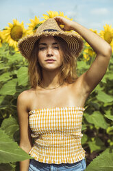 Junge Frau mit einem Strohhut auf dem Kopf in einem Sonnenblumenfeld - ACPF00328