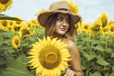 Junge Frau mit Strohhut lächelnd in einem Sonnenblumenfeld - ACPF00329