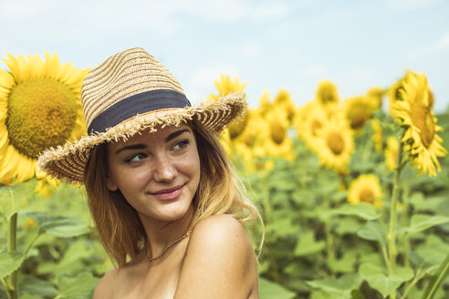 Junge Frau mit Strohhut lächelnd in einem Sonnenblumenfeld - ACPF00330