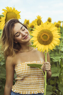 Junge Frau hält lächelnd eine Sonnenblume - ACPF00333
