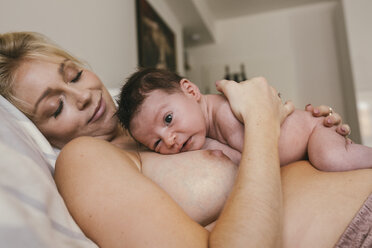 Newborn baby lying skin to skin with mother in bed - MFF04589