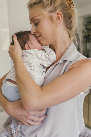 Glückliche Mutter, die ihr Baby an der Schulter hält, lizenzfreies Stockfoto