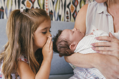 Mutter hält ihr Baby im Arm und Schwester flüstert ihm zu - MFF04600