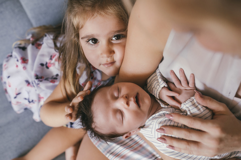 Mother holding her baby close with sister feeling his hair stock photo