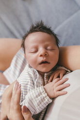 Portrait of newborn baby with closed eyes being held by mother - MFF04604