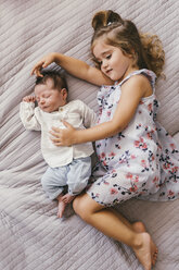 Mädchen liegt auf einer Decke und kuschelt mit ihrem kleinen Bruder - MFF04615