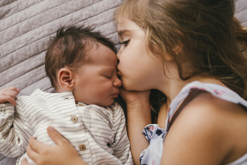 Liebevolles Mädchen, das auf einer Decke liegt und mit ihrem kleinen Bruder kuschelt - MFF04619