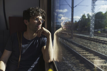 Man traveling by train looking out of window - KKAF01778