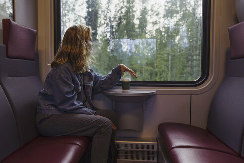 Woman traveling by train looking out of window - KKAF01784