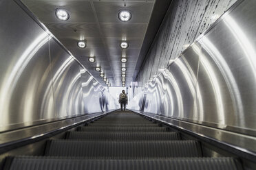 Rückenansicht einer Frau, die auf einer Rolltreppe einer U-Bahn-Station steht - KKAF01787