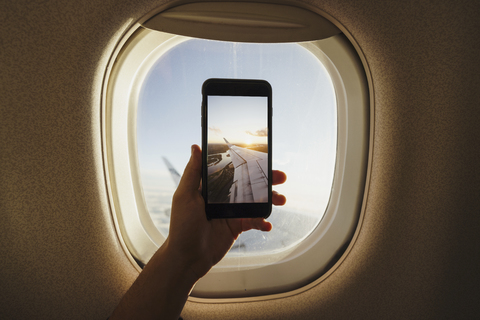 Hand nimmt Handy-Foto aus dem Flugzeugfenster, lizenzfreies Stockfoto