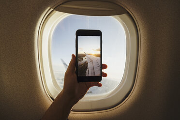 Hand nimmt Handy-Foto aus dem Flugzeugfenster - KKAF01793