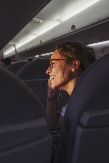 Laughing young woman in a plane in sunshine - KKAF01800