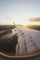 Blick aus dem Fenster auf die Tragfläche eines Flugzeugs bei Sonnenuntergang - KKAF01801