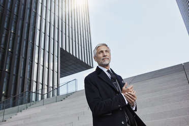 Portrait of mature businessman standing on stairs outdoors - RORF01470